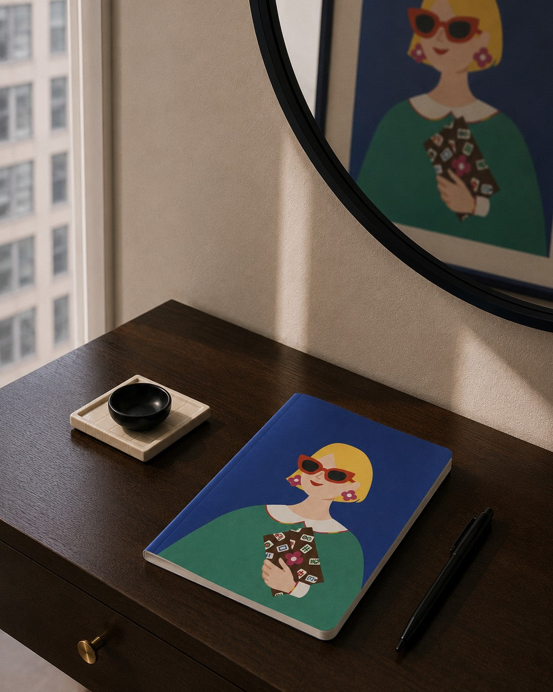 Lucky Tiles soft cover journal displayed on a modern apartment entry console with a black pen, decorative tray, and framed art print in the background