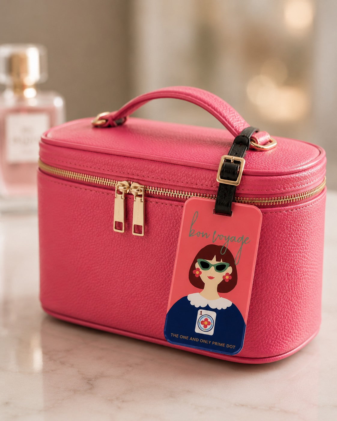 The One and Only Prime Dot luggage tag attached to a pink travel cosmetic bag