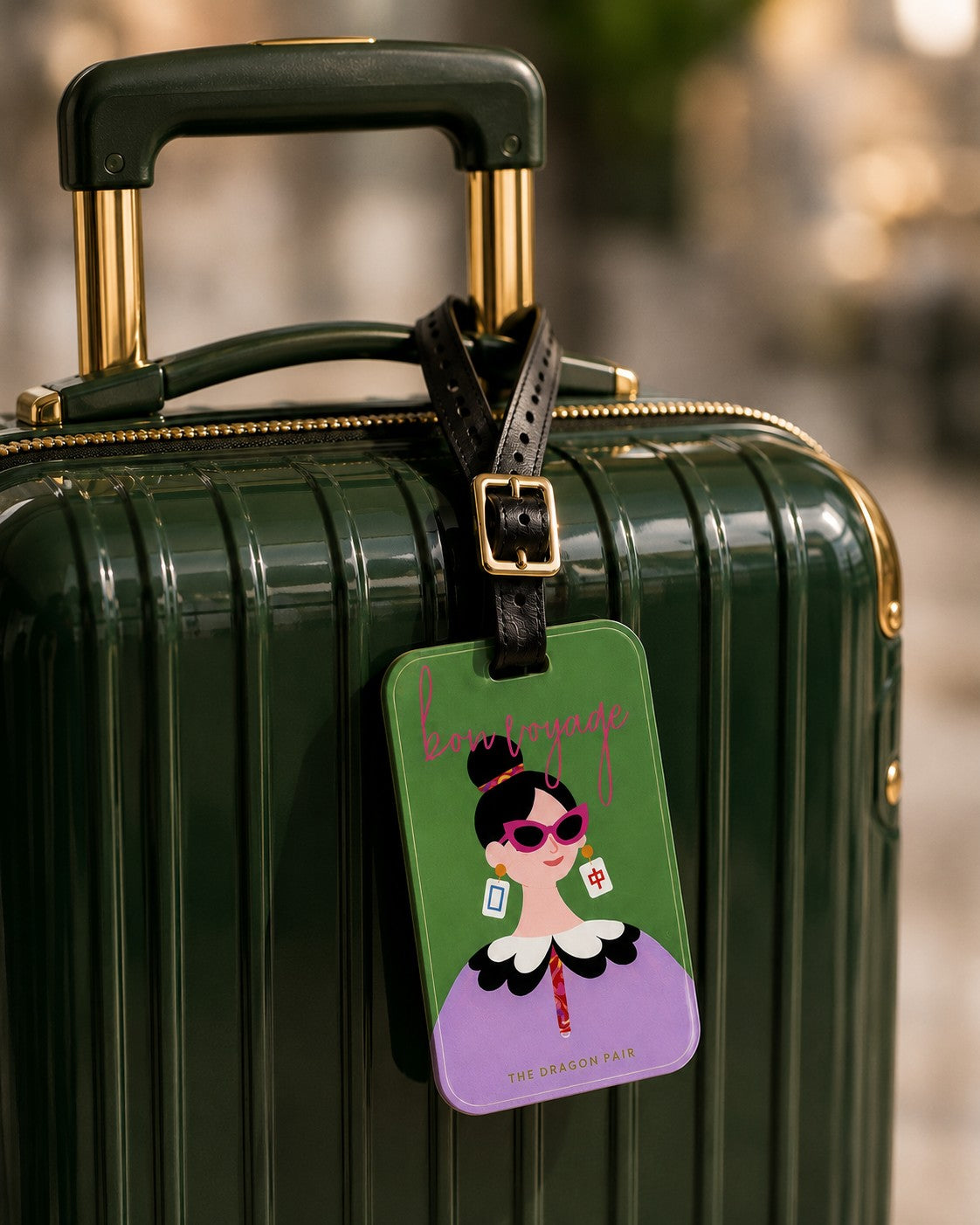 The Dragon Pair luggage tag attached to a suitcase handle during travel